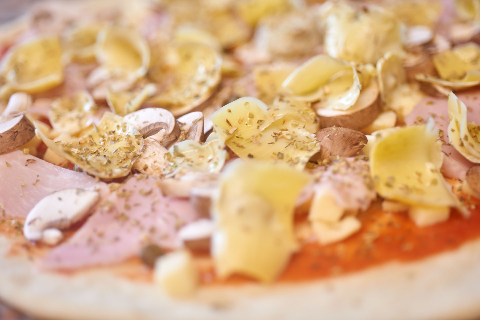 Close up of raw ingredients waiting to be put into pizza oven