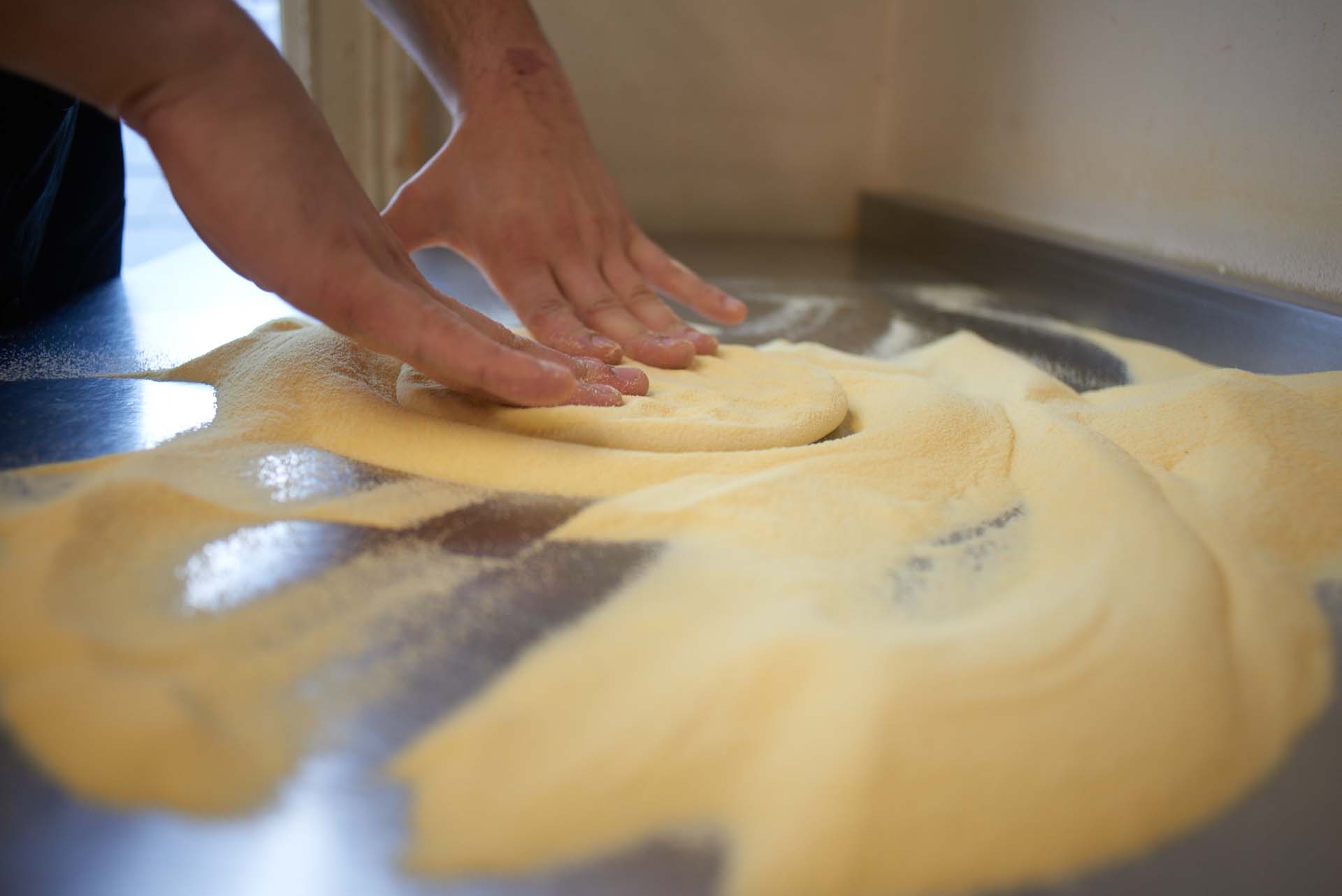 Chef shaping pizza dough into round base